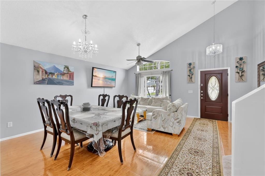 A dining area with a table and chairs sits in front of a living room space — 3047 STILLWATER DRIVE, KISSIMMEE, FL