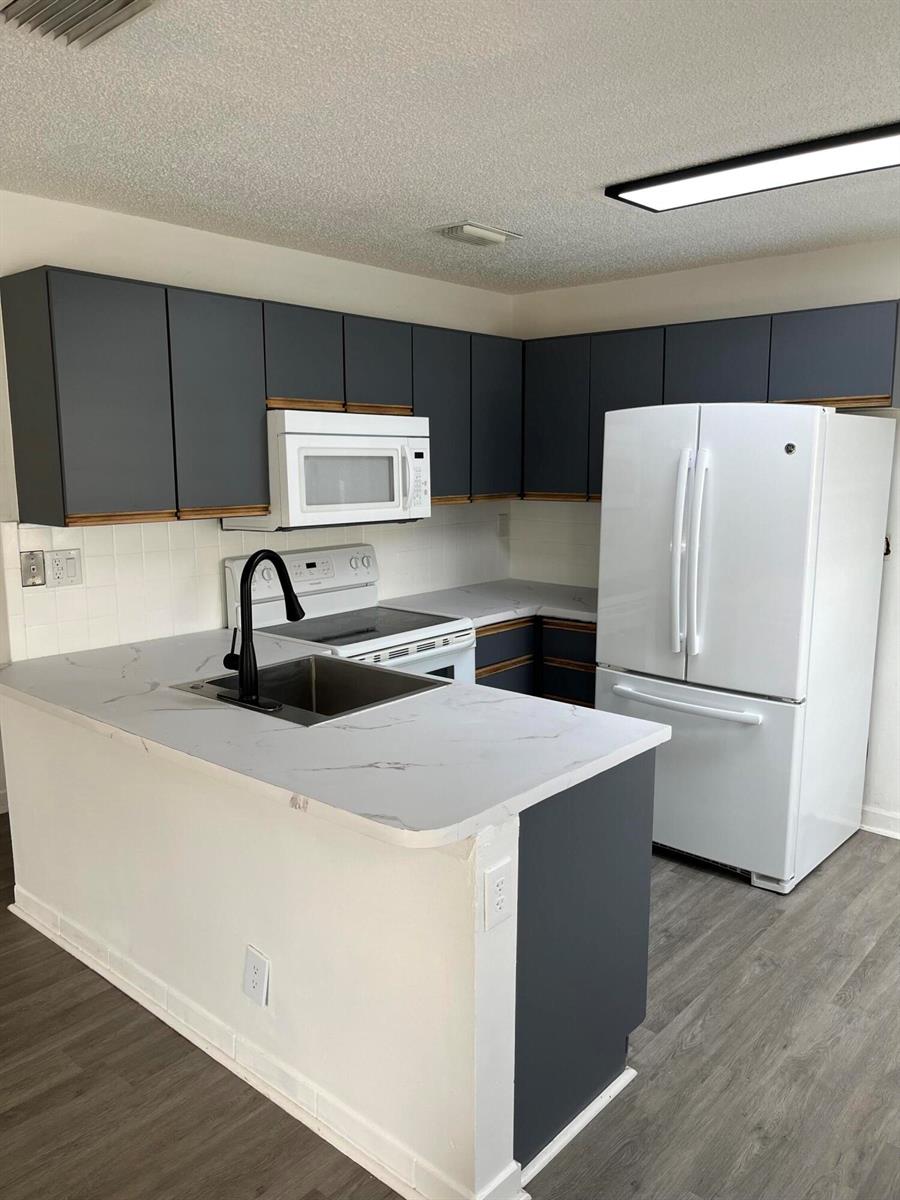 A kitchen features dark gray cabinets, white appliances, and a white marble-patterned countertop — 5665 Boynton Cove Way, Boynton Beach FL 33437, BOYNTON BEACH, FL