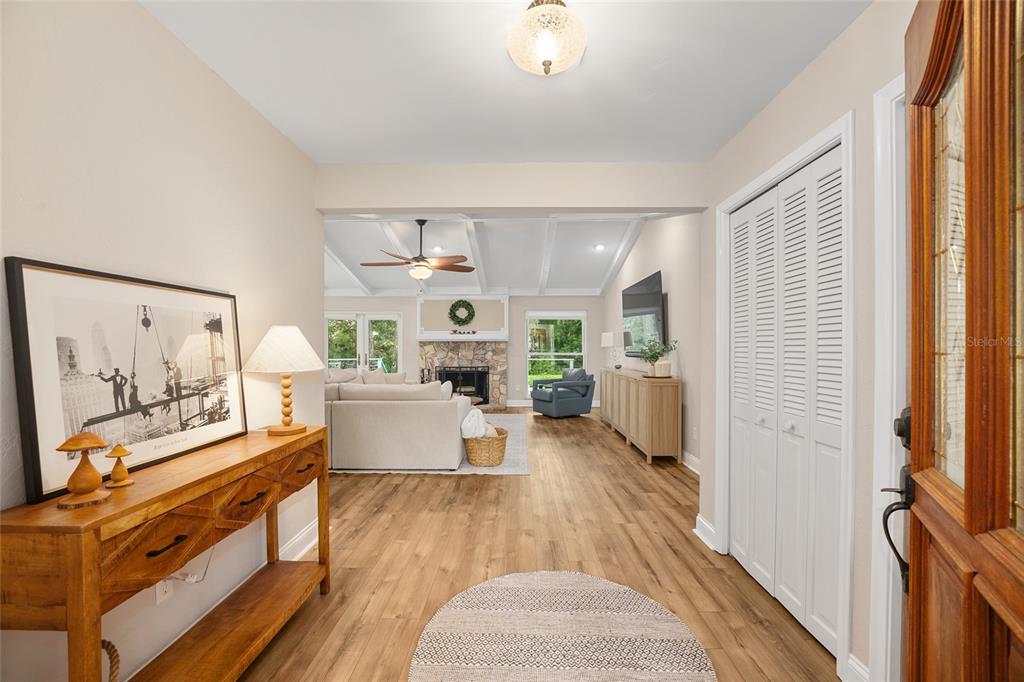 A bright entryway with wood-look flooring leads into a living room with a stone fireplace — 8140 NW 48TH LANE, OCALA, FL