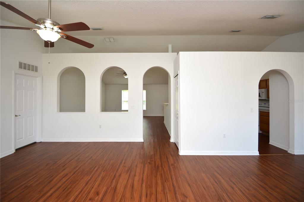 An empty room with wood-look flooring, a ceiling fan, and several arched wall openings — 36 FRENORA LANE, PALM COAST, FL