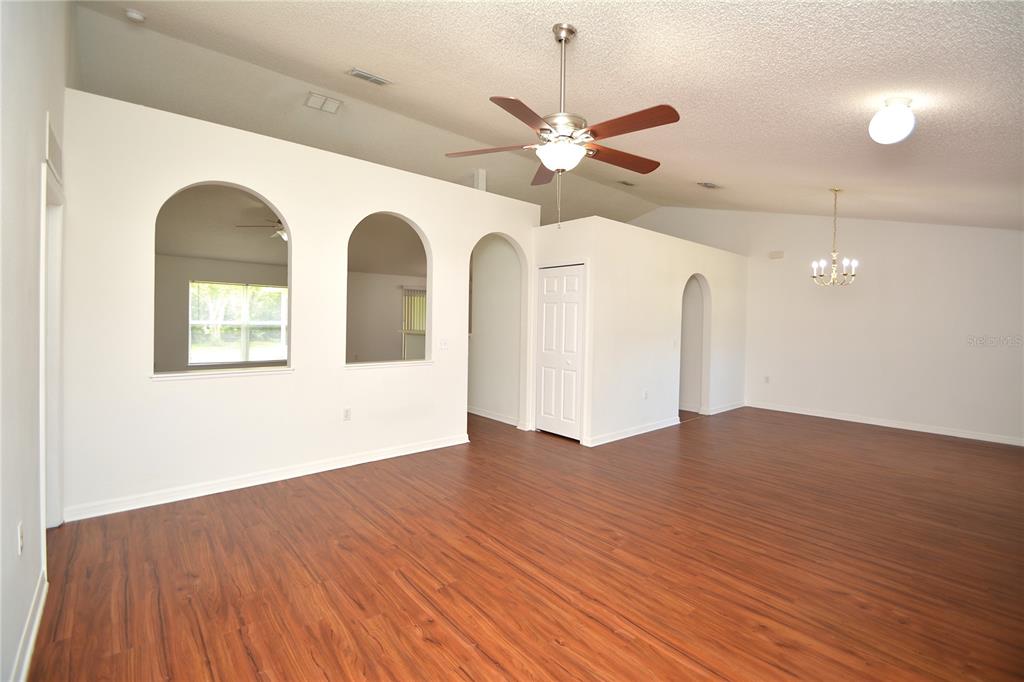 A spacious living area features vaulted ceilings, arched wall cutouts, and wood-look laminate flooring — 36 FRENORA LANE, PALM COAST, FL