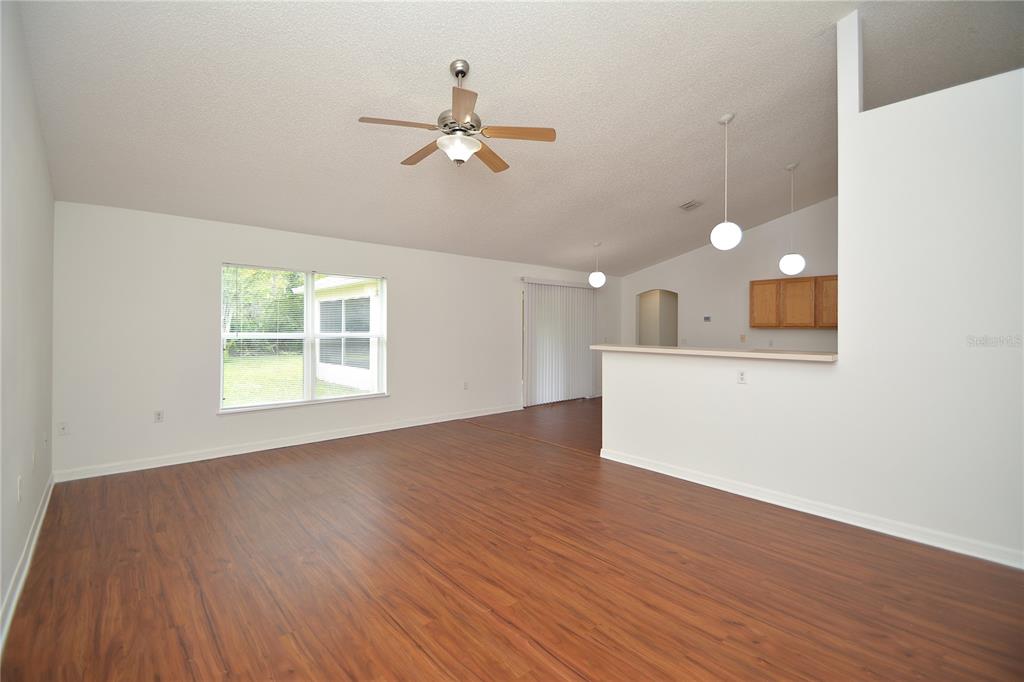 An open-concept living area features wood-look flooring, a ceiling fan, and a kitchen breakfast bar — 36 FRENORA LANE, PALM COAST, FL