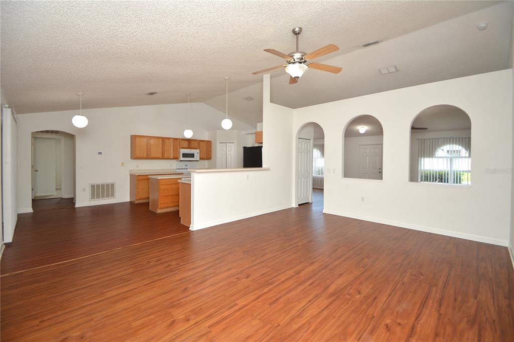 An open-concept living room and kitchen with wood-look flooring, white walls, and arched wall openings — 36 FRENORA LANE, PALM COAST, FL