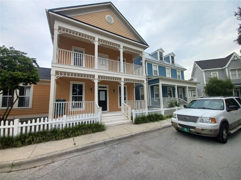 A two-story yellow house with a double-decker porch stands next to a blue house — 1010 PERIWINKLE COURT, CELEBRATION, FL
