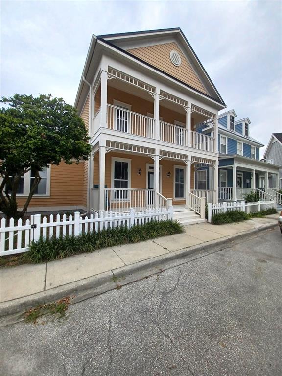 A two-story yellow house with a double-decker front porch and a white picket fence — 1010 PERIWINKLE COURT, CELEBRATION, FL