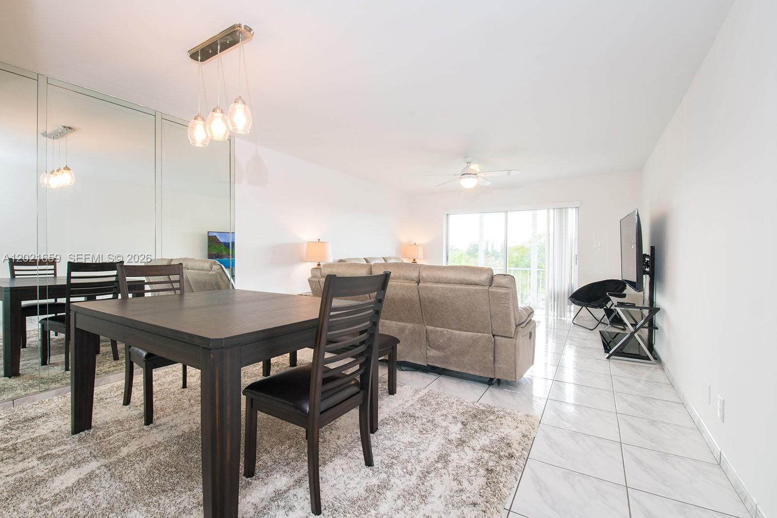 A dining area with a dark wood table and chairs sits before a living room — 4650 Washington St # 502, Hollywood FL 33021, HOLLYWOOD, FL