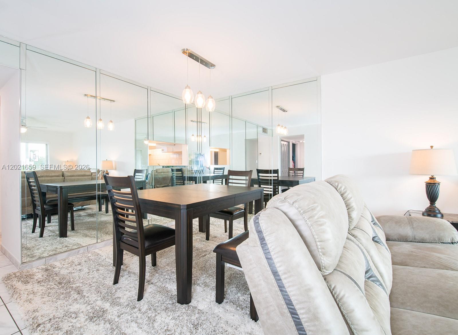 A dining area features a dark wood table and chairs in front of a mirrored wall — 4650 Washington St # 502, Hollywood FL 33021, HOLLYWOOD, FL