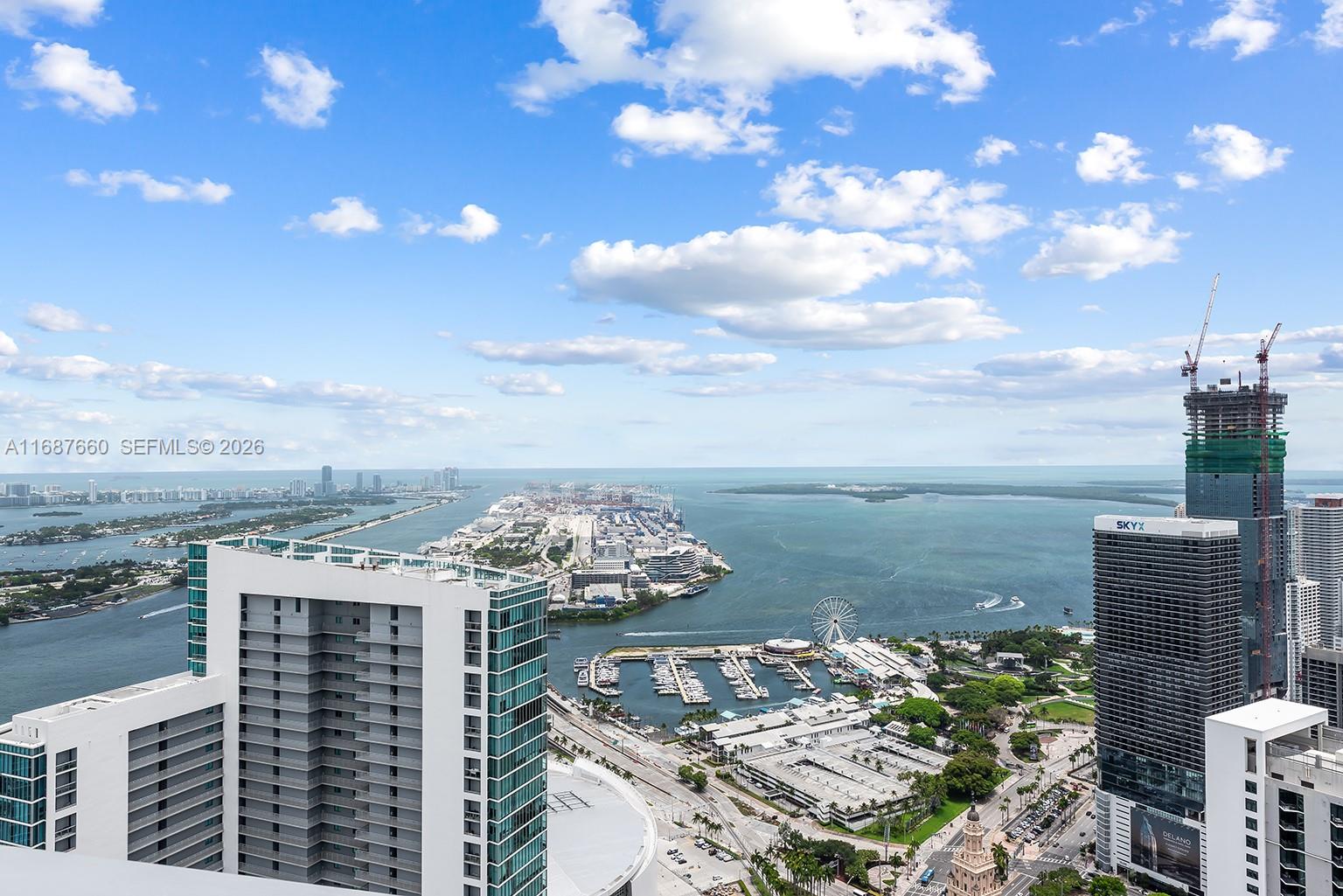 An elevated view shows a harbor, a Ferris wheel, and skyscrapers under a cloudy sky — 851 NE 1st Ave # 5700, Miami FL 33132, MIAMI, FL