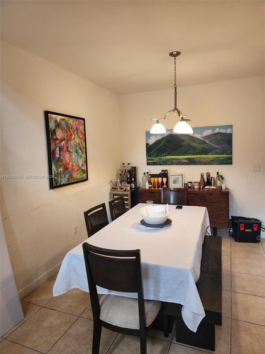 A kitchen features wooden cabinets, stainless steel appliances, a granite breakfast bar, and tiled floors — 7510 NW 107th Pl, Doral FL 33178, DORAL, FL