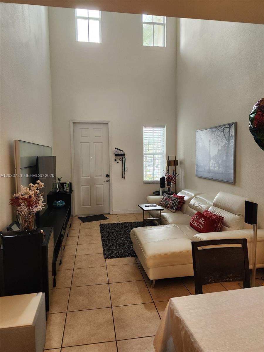 A kitchen features wooden cabinets, granite countertops, stainless steel appliances, and two white bar stools — 7510 NW 107th Pl, Doral FL 33178, DORAL, FL