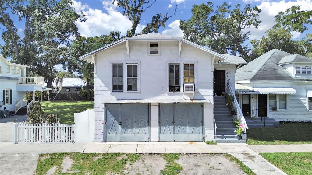 A two-story white house features two ground-level garage doors and an exterior staircase leading upstairs — 601 W BAKER ST, PLANT CITY, FL