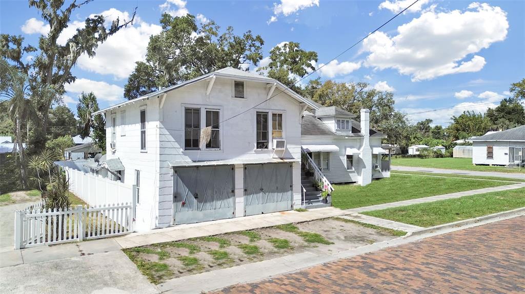 A two-story white house with a double garage and a white picket fence — 601 W BAKER ST, PLANT CITY, FL