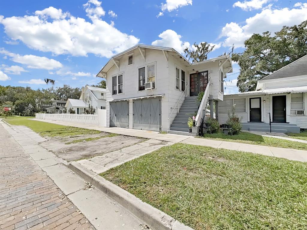A white two-story house with a brick street, garage doors, and an exterior staircase — 601 W BAKER ST, PLANT CITY, FL