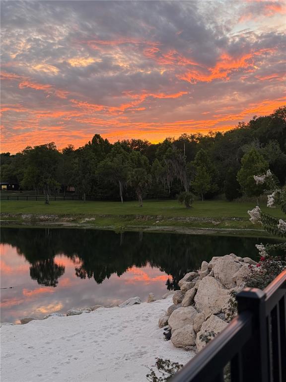 A view of a pond and sandy beach at sunset with trees in the background — 17995 NE 24TH TERRACE, CITRA, FL