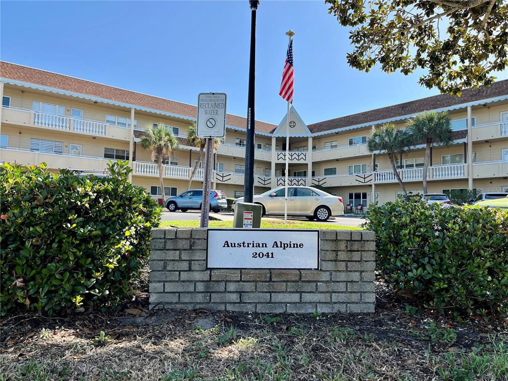 A brick sign for Austrian Alpine stands in front of a multi-story apartment building — 2041 AUSTRALIA WAY W UNIT 49, CLEARWATER, FL