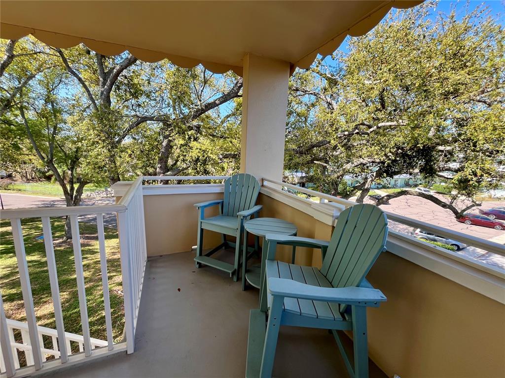 A covered balcony features two light blue Adirondack chairs and a small matching side table — 2041 AUSTRALIA WAY W UNIT 49, CLEARWATER, FL