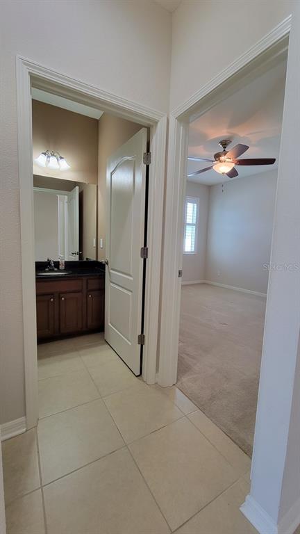 A tiled hallway leads to a bathroom with a dark vanity and an adjacent carpeted bedroom — 2229 VALTERRA VISTA WAY, VALRICO, FL