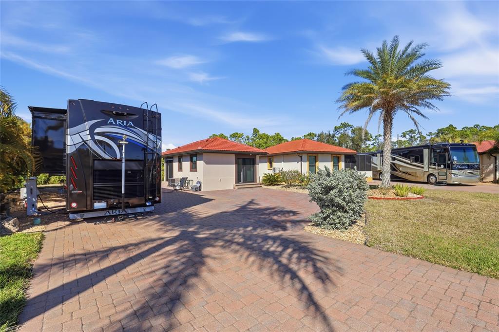 A paved driveway features two large recreational vehicles parked in front of a single-story house — 14100 MYAKKA AVENUE UNIT 26, PORT CHARLOTTE, FL