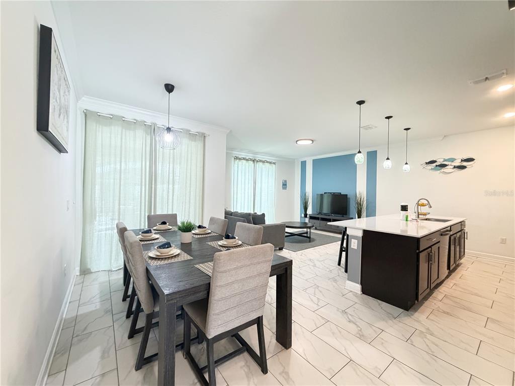 An open-concept dining area and kitchen with tile flooring and a dark wood dining table — 4192 PARAGRAPH DRIVE, KISSIMMEE, FL