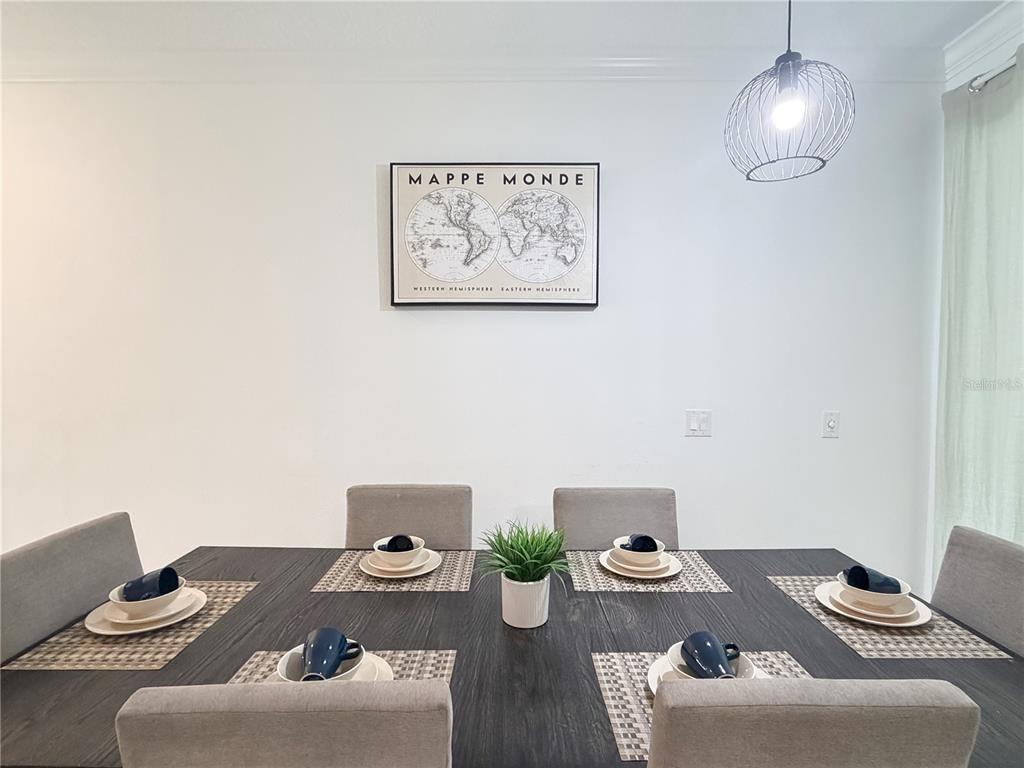 A dining room features a dark wood table with six place settings and a world map — 4192 PARAGRAPH DRIVE, KISSIMMEE, FL