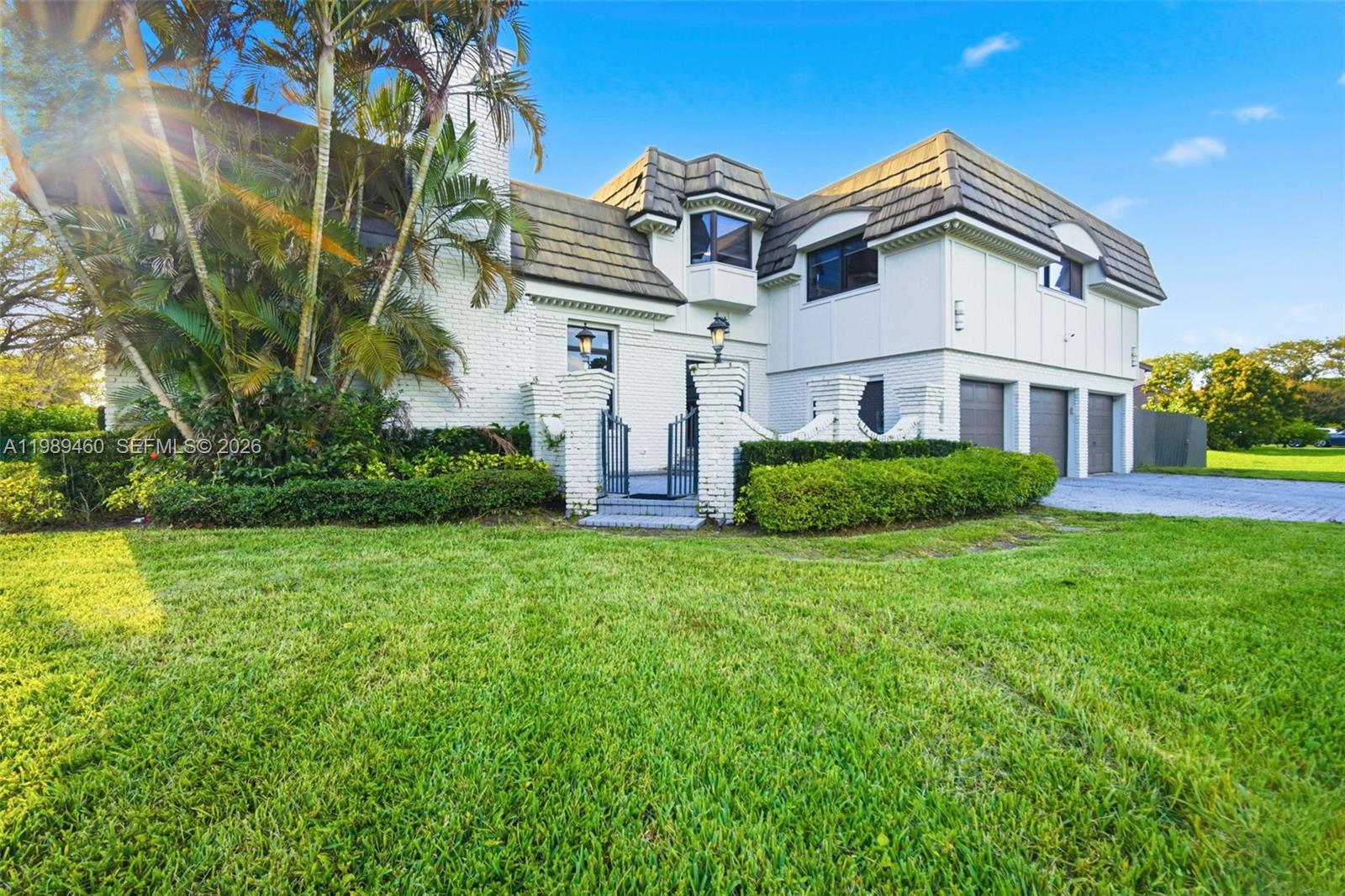 A two-story house with a white brick facade, a dark shingled roof, and a gated entrance — 2201 SW 115th Ter, Davie FL 33325, DAVIE, FL