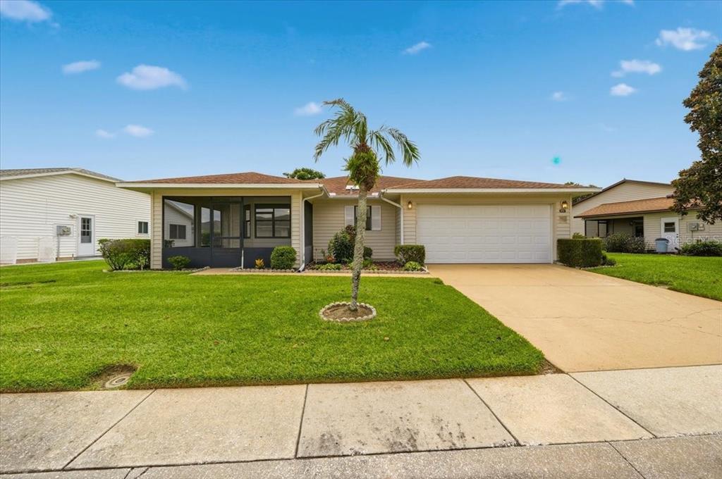 A single-story house with a screened-in porch, a palm tree, and a two-car garage — 3741 INNISBROOK DRIVE, LAKELAND, FL