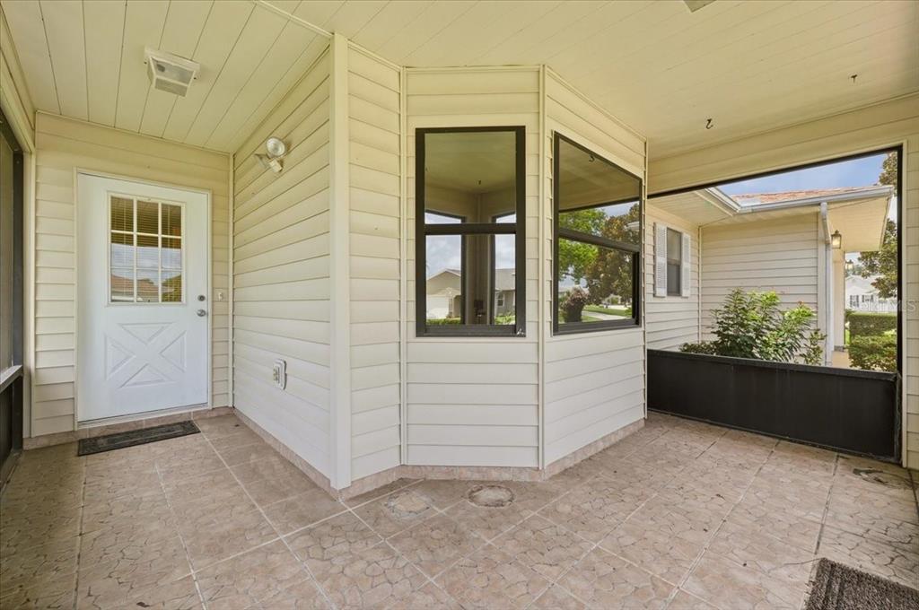 A covered patio with light-colored siding, a white door, and tiled flooring — 3741 INNISBROOK DRIVE, LAKELAND, FL