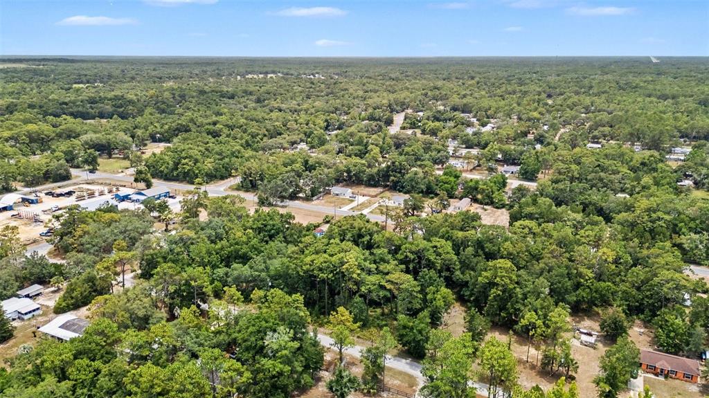 An aerial view shows a rural residential area surrounded by dense forest and scattered buildings — 7078 W LINCOLN LANE, HOMOSASSA, FL