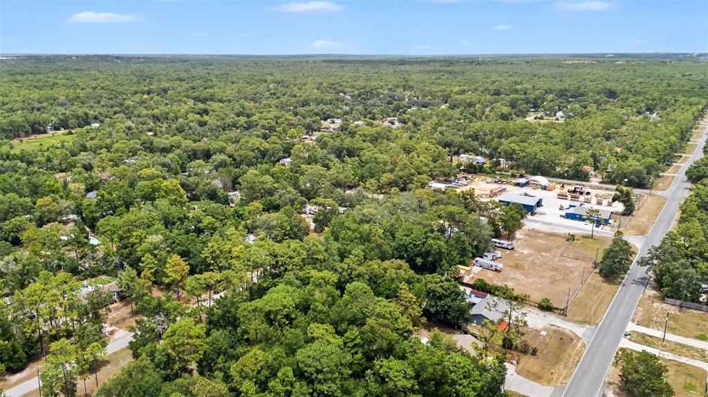 An aerial view shows a wooded area with scattered houses and a commercial property nearby — 7078 W LINCOLN LANE, HOMOSASSA, FL