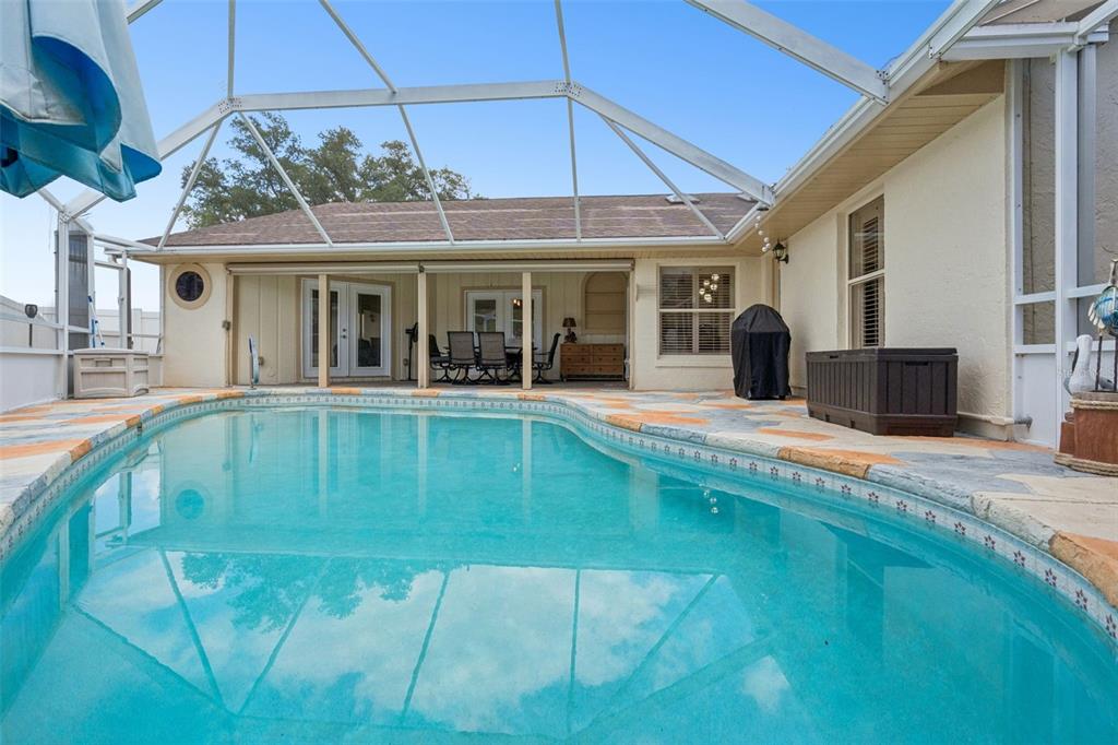 A screened-in patio features a swimming pool, stone-patterned decking, and outdoor dining furniture — 33939 VALENCIA DRIVE, LEESBURG, FL