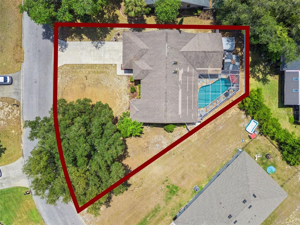 This aerial view shows a house with a pool and driveway on a triangular lot — 33939 VALENCIA DRIVE, LEESBURG, FL