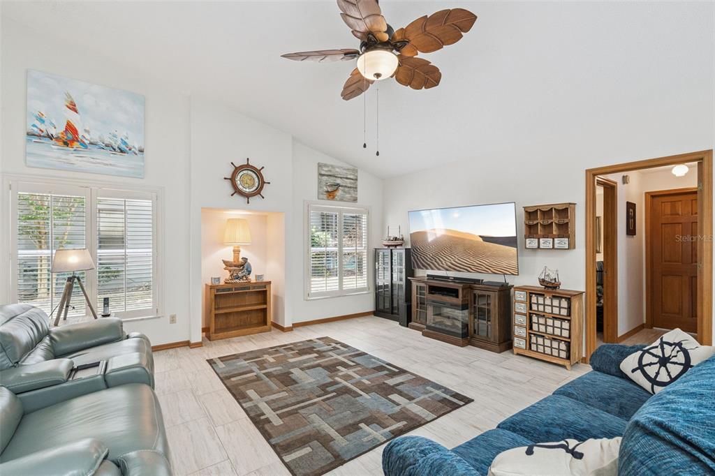 A living room with light tile floors, a ceiling fan, and a large television — 33939 VALENCIA DRIVE, LEESBURG, FL