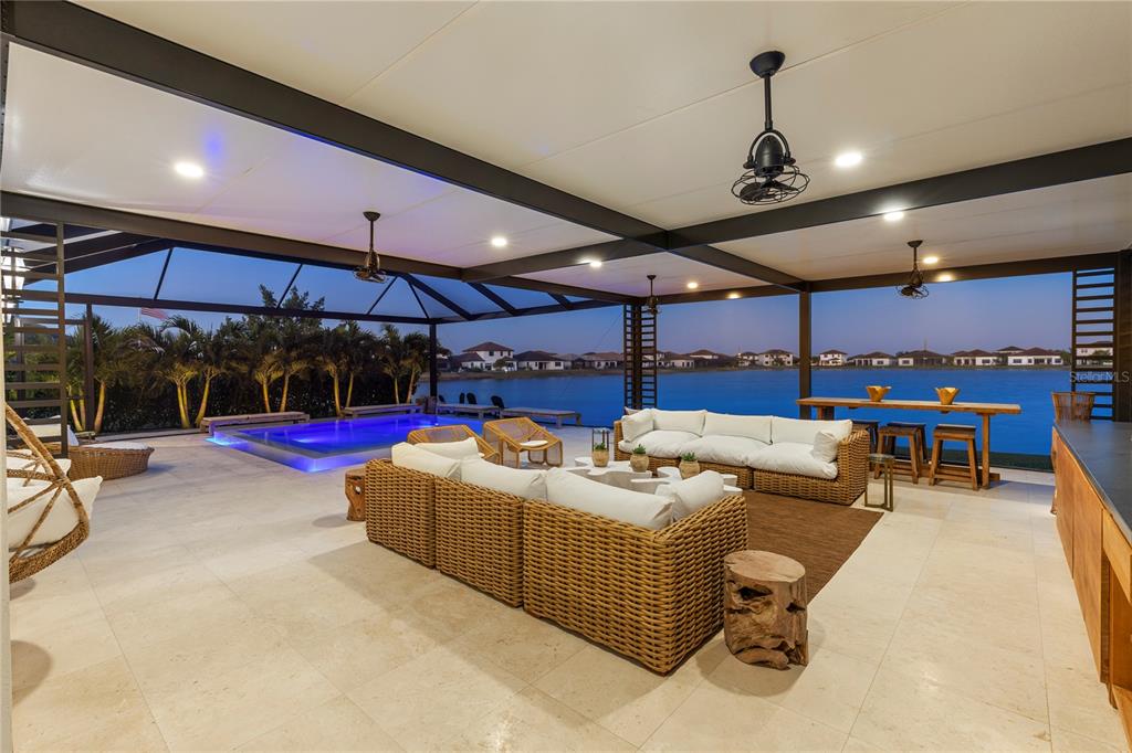 A covered outdoor patio features a swimming pool, wicker furniture, and a view of water — 4796 SOPHIA DRIVE, AVE MARIA, FL