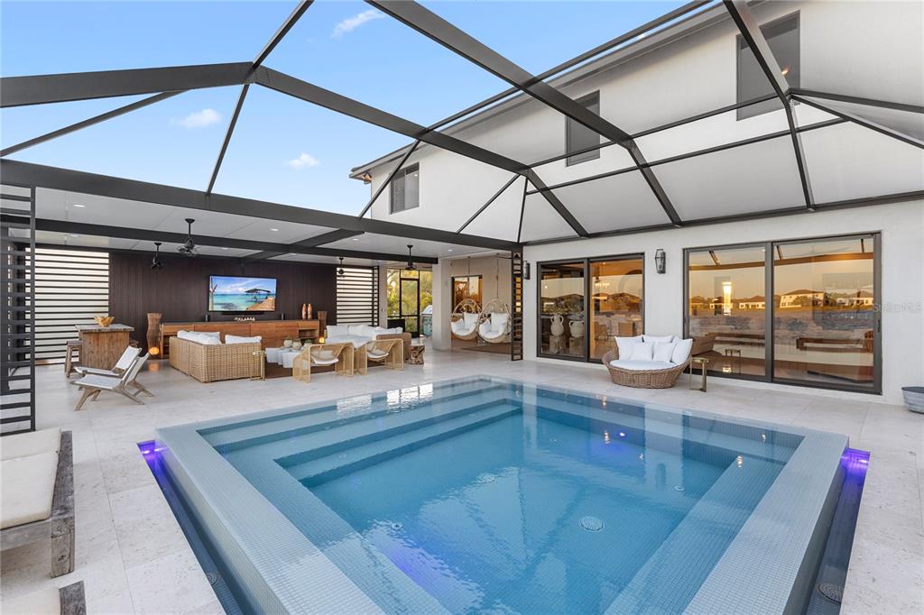 A covered patio features a swimming pool, outdoor seating, a television, and hanging chairs — 4796 SOPHIA DRIVE, AVE MARIA, FL