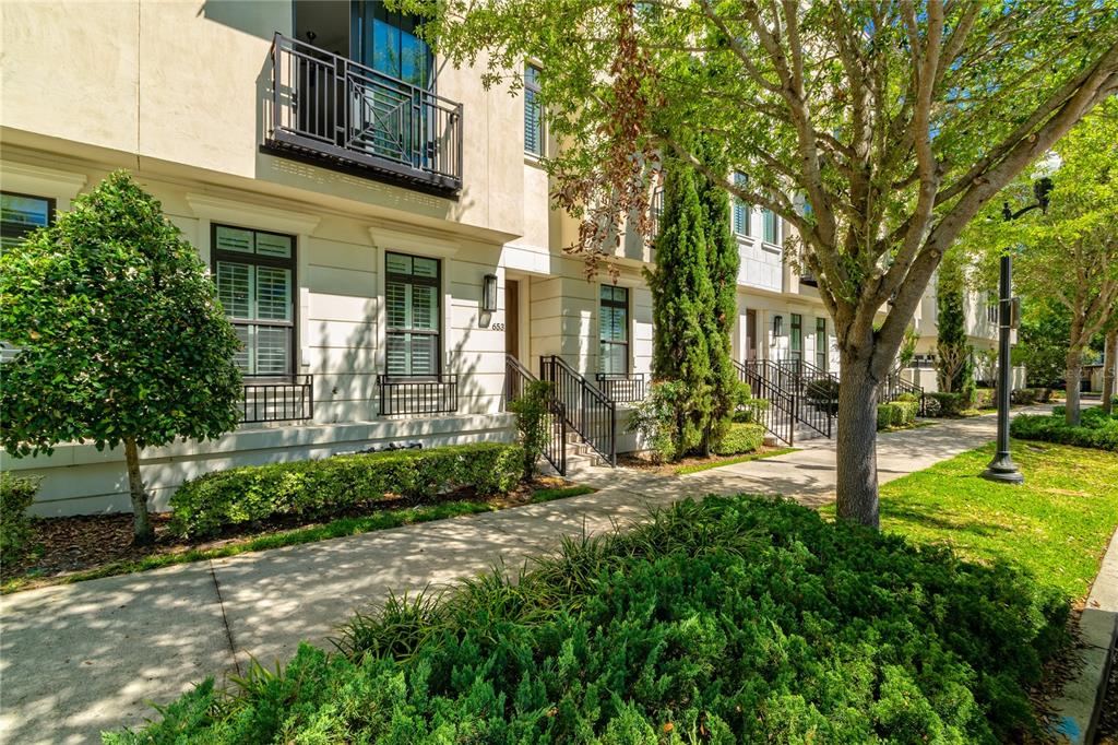 A sidewalk leads past the front entrances of multi-story townhomes with balconies and landscaping — 653 E JACKSON STREET, ORLANDO, FL
