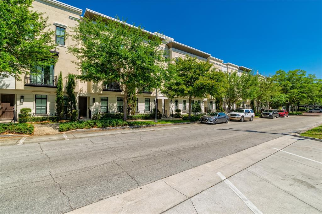 A row of multi-story townhouses with balconies and trees lining a paved street — 653 E JACKSON STREET, ORLANDO, FL
