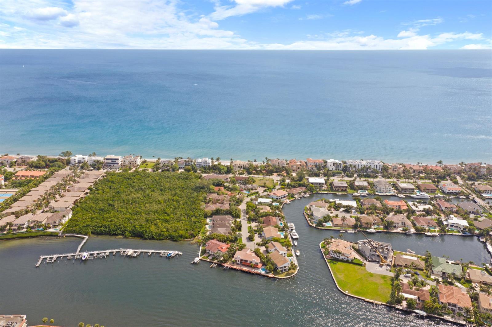 An aerial view shows waterfront homes, a canal, a large wooded area, and the ocean — 4102 S Ocean Boulevard, Highland Beach FL 33487, HIGHLAND BEACH, FL