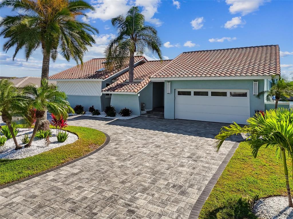 A single-story house with a tiled roof, light blue siding, and a paved driveway — 320 BELLE ISLE AVENUE, BELLEAIR BEACH, FL