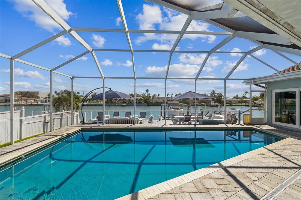 A white outdoor dining set sits on a gray deck overlooking a waterfront canal — 320 BELLE ISLE AVENUE, BELLEAIR BEACH, FL