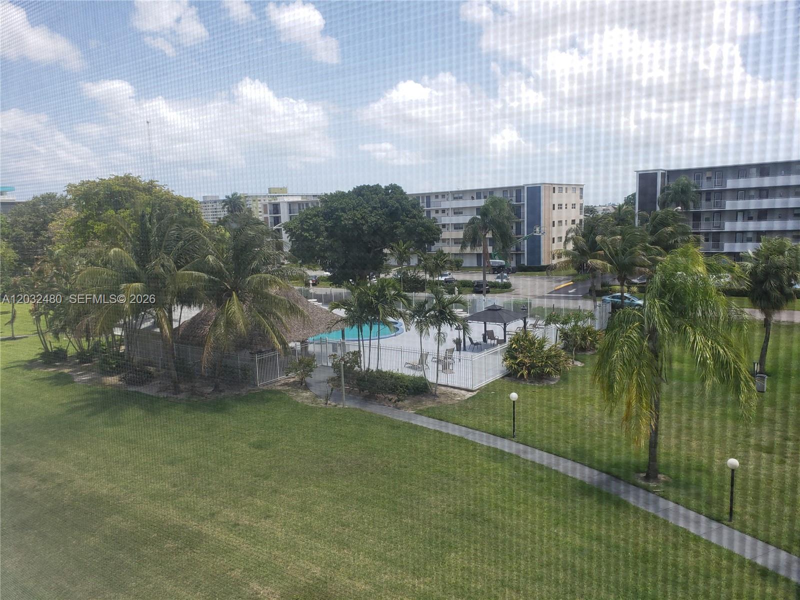 An elevated view shows a swimming pool area with palm trees and apartment buildings — 4700 Washington St # 404, Hollywood FL 33021, HOLLYWOOD, FL