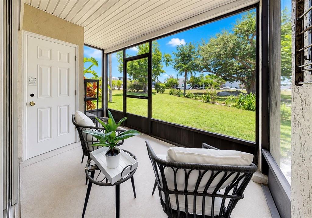 A screened-in patio features two chairs, a small table with a plant, and a grassy view — 1028 APOLLO BEACH BOULEVARD UNIT 102, APOLLO BEACH, FL