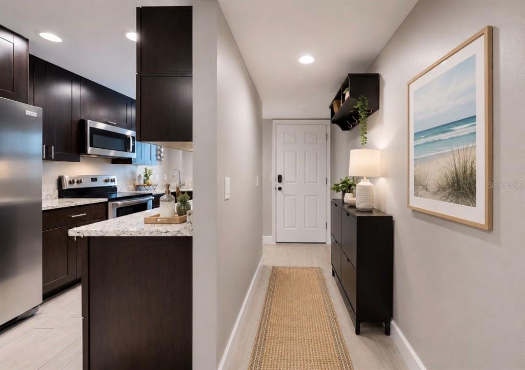 A hallway with a shoe cabinet and wall art leads to a white front door — 1028 APOLLO BEACH BOULEVARD UNIT 102, APOLLO BEACH, FL
