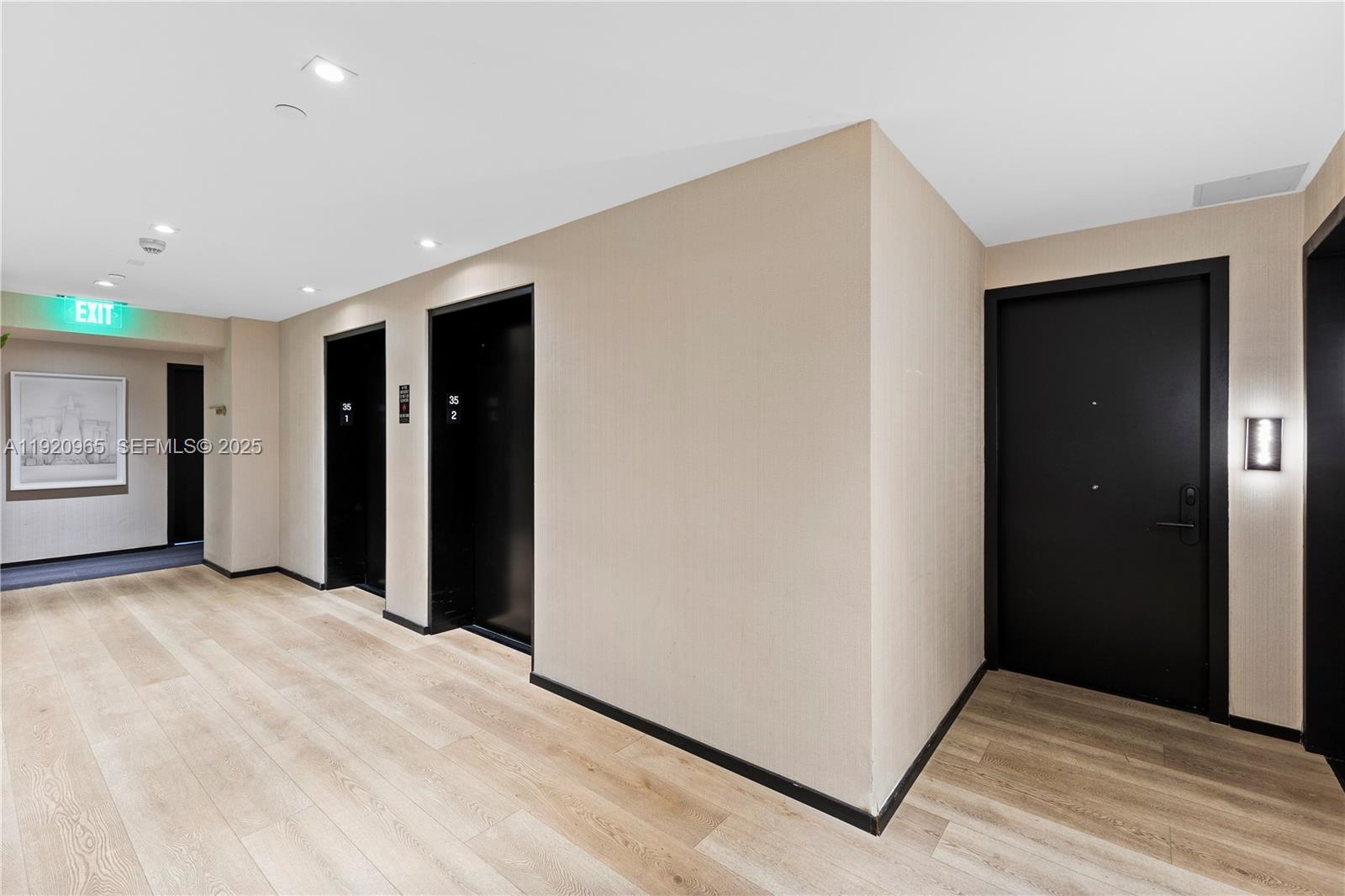 A hallway features light wood flooring, beige walls, two black elevator doors, and a black entrance door — 398 NE 5th St # 3515, Miami FL 33132, MIAMI, FL