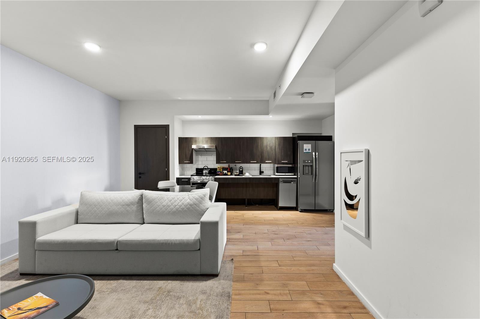 A modern open-concept living room and kitchen featuring dark cabinetry and light wood flooring — 398 NE 5th St # 3515, Miami FL 33132, MIAMI, FL
