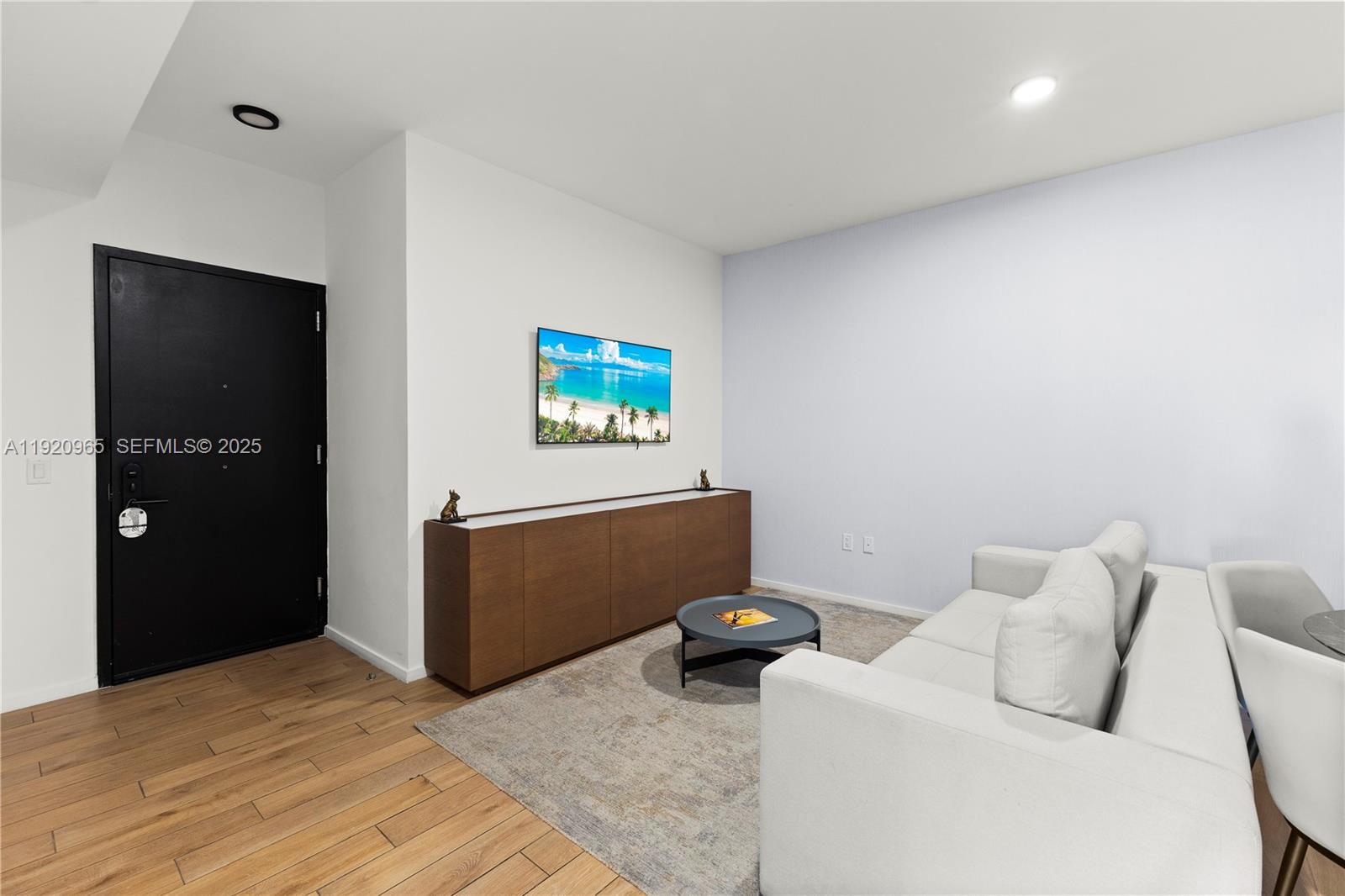 A living room features a white sofa, a wooden media console, and a wall-mounted television — 398 NE 5th St # 3515, Miami FL 33132, MIAMI, FL