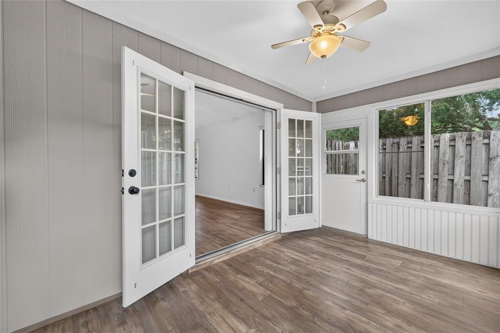 A sunroom with wood-look flooring, a ceiling fan, and French doors leading to the interior — 3928 NE 22ND STREET, OCALA, FL