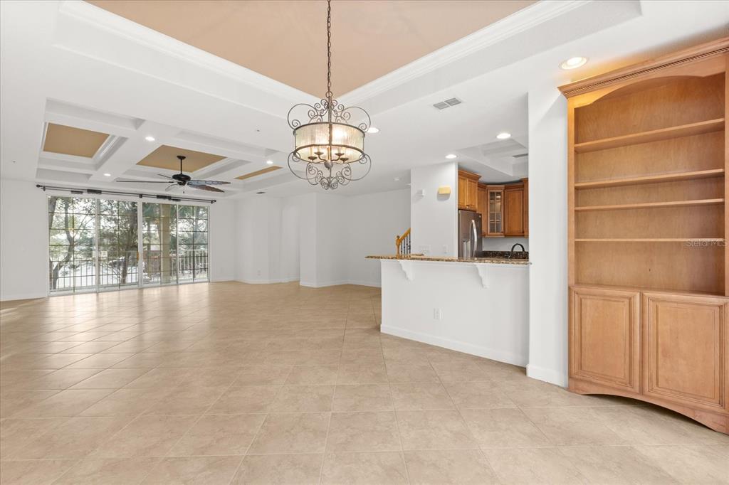An open-concept living area features tile flooring, a coffered ceiling, and a built-in wooden bookshelf — 1125 BOLTON PLACE, LAKE MARY, FL