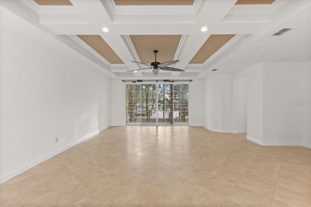 A spacious room features a coffered ceiling, tile flooring, and sliding glass doors to a patio — 1125 BOLTON PLACE, LAKE MARY, FL