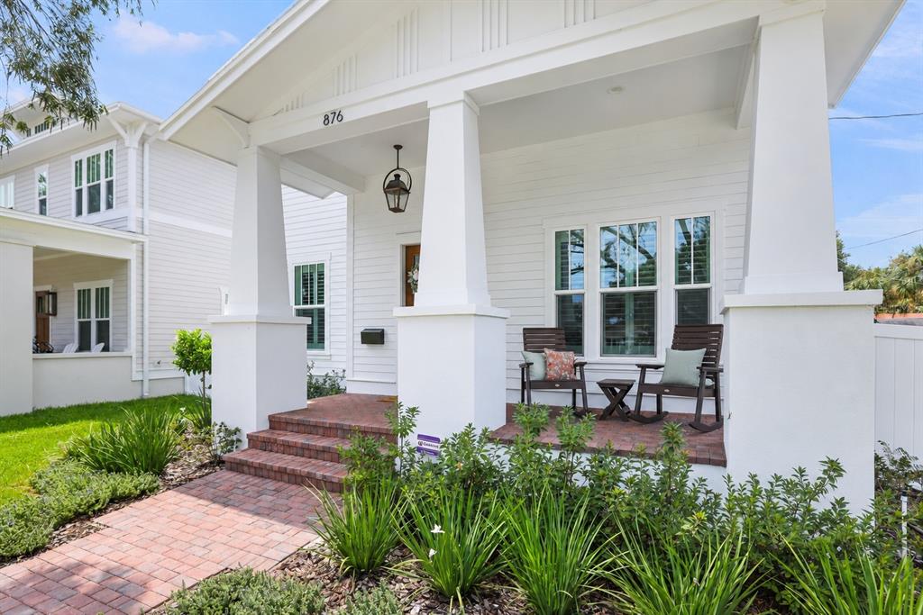 A white house exterior features a brick porch with two rocking chairs and large columns — 876 44TH AVENUE N, ST PETERSBURG, FL