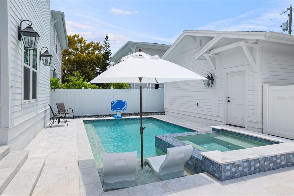 A backyard features a swimming pool with a spa, lounge chairs, and a white umbrella — 876 44TH AVENUE N, ST PETERSBURG, FL